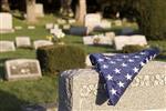 American flag folded over a gravestone in a cemetery.